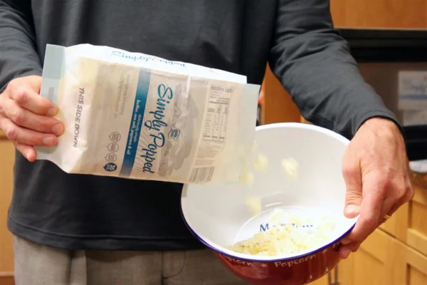 dumping microwave popcorn kernels into a bowl